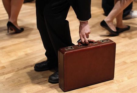 © Reuters. A man grabs his briefcase as he waits in line to speak with employers at the UJA-Federation Connect to Care job fair in New York