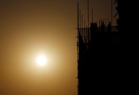 © Reuters. Labourers working on a construction site are seen next to setting sun in Beijing