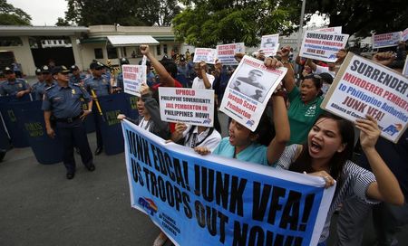 © Reuters. Protesters march past the policemen during a rally against the killing of Filipino transgender Jennifer Laude, outside the U.S. embassy in Manila