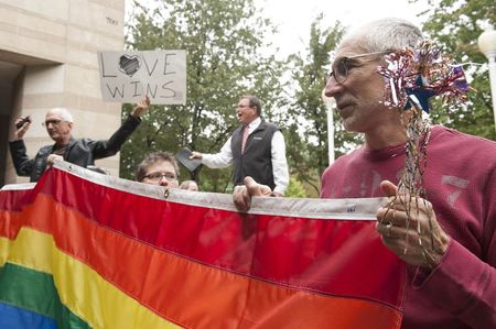 © Reuters. Larry Ferri and Brandi Morris hold large rainbow flag as gay couples marry outside of Mecklenburg County Register of Deeds office in Charlotte