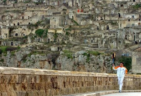 © Reuters. Runner carries Olympic torch past Sassi dwellings in UNESCO world heritage site of Matera