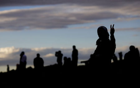 © Reuters. A Turkish Kurd shows a victory sign as he watches the Syrian town of Kobani