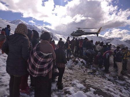 © Reuters. Handout photo of people gathering near a helicopter belonging to Nepal Army used to rescue avalanche victims at Thorang-La in Annapurna Region