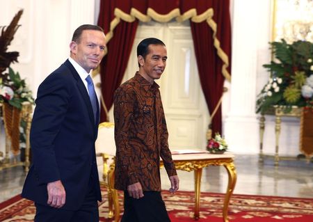 © Reuters. Indonesia's new President Joko Widodo walks beside Australia's Prime Minister Tony Abbott after a meeting at the presidential palace in Jakarta