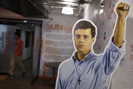 © Reuters. A man walks behind a cardboard figure of jailed opposition leader Lopez at the headquarters of political party Popular Will in Caracas