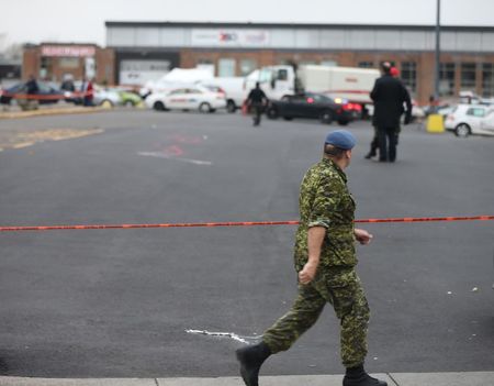 © Reuters. A member of Canada's armed forces walks past the scene of a hit and run of two soldiers in St. Jean sur Richelieu