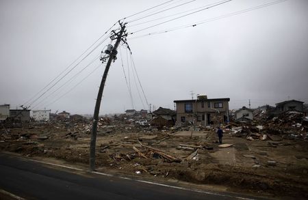 © Reuters. File photo of a man walking near a damaged power pole in Watari