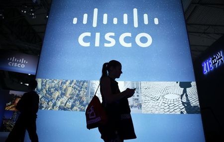 © Reuters. A visitor walks past a Cisco advertising panel as she looks at her mobile phone at the Mobile World Congress in Barcelona