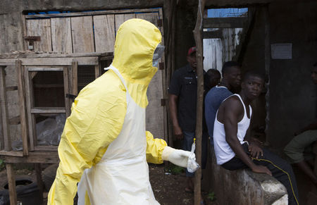 © Reuters. Health worker in protective equipment carries a sample taken from the body of someone who is suspected to have died from Ebola virus, near Rokupa Hospital