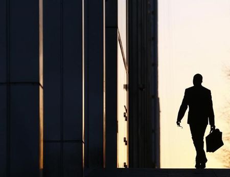 © Reuters. A worker arrives at his office in the Canary Wharf business district in London