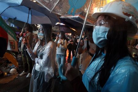 © Reuters. Pro-democracy protesters stand in heavy rain while blocking a main road at Mongkok shopping district in Hong Kong