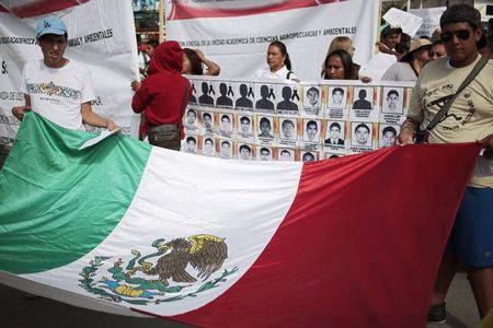 © Reuters. People hold a Mexican flag during a demonstration to demand information for the 43 missing students of the Ayotzinapa teachers' training college, in Iguala