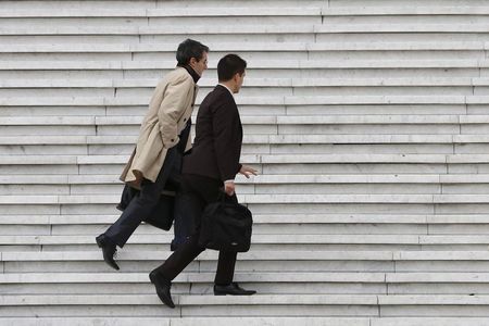 © Reuters. Businessmen carry briefcases as they climb the stairs under the Arche de la Defense in the financial and business district west of Paris