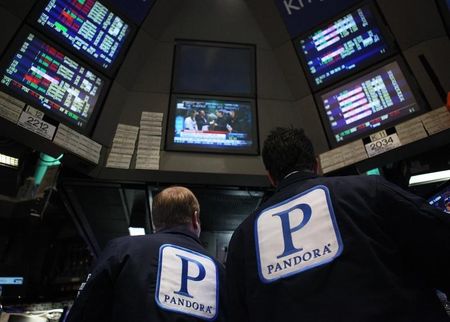 © Reuters. Traders work at the kiosk where Pandora internet radio is traded on the floor of the New York Stock Exchange