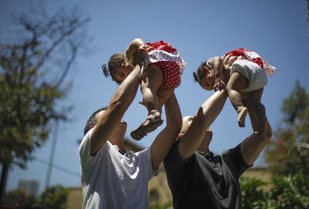 © Reuters. Jason Howe and Adrian Perez hold their twin daughters Clara and Olivia at a playground in West Hollywood