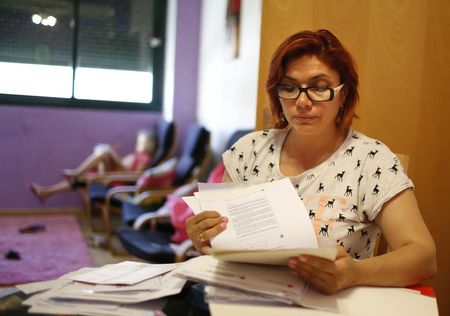 © Reuters. Unemployed hairdresser and mother-of-three Yasmin Rubiano looks at documents at her flat in Madrid