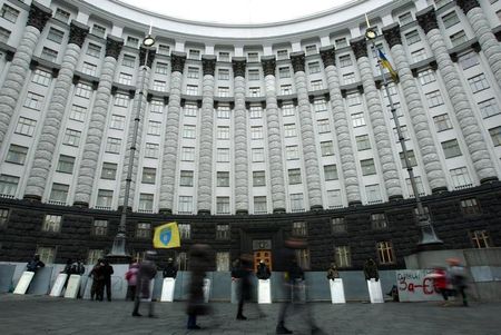 © Reuters. People walk past the government headquarters as members of self defence units stand guard in Kiev