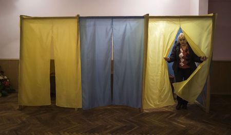 © Reuters. A staff member of a local community center, converted to a polling station, walks out of a voting cabin in the village of Novotroits'ke