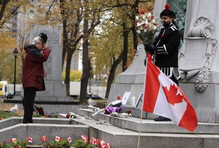 © Reuters. Man takes off his cap as he pays his respects to fallen Canadian soldiers, Warrant Officer Vincent and Corporal Cirillo during a vigil in Montreal