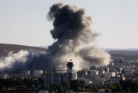© Reuters. Turkish flag atop a grain silo flutters as thick smoke bellows following an air strike in Kobani