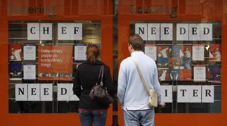 © Reuters. Pedestrians read recruitment announcements in central London