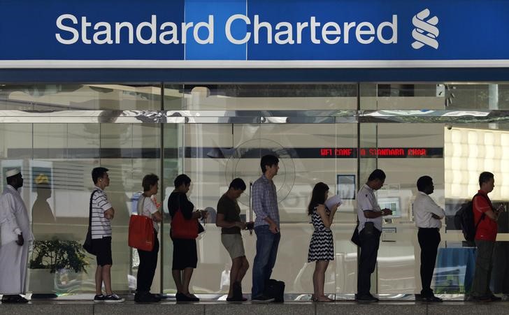 &copy; Reuters People queue up outside a Standard Chartered Bank branch before operation hours at the central business district in Singapore