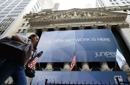 © Reuters. A woman walks past a banner with the logo of Juniper Networks Inc. covering the facade of the New York Stock Exchange