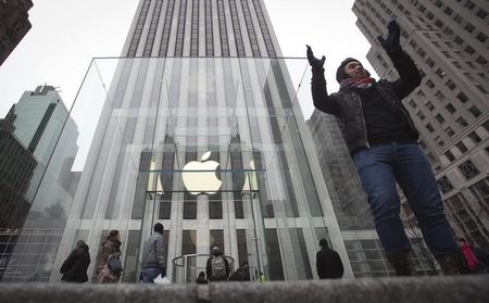 © Reuters. A man poses for a photo in front of the Apple store on 5th Avenue in New York