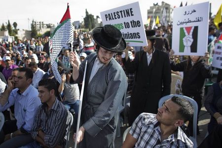 © Reuters. An ultra-Orthodox Jewish man exchanges looks with a Palestinian man during a rally in the West Bank city of Ramallah