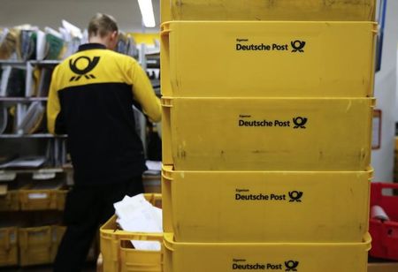 © Reuters. Transport boxes are pictured next to a Deutsche Post postman in Berlin
