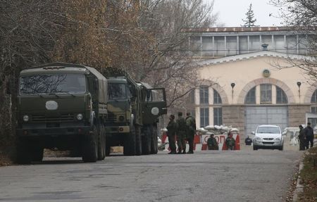 © Reuters. Вооруженные люди стоят у грузовиков без опознавательных знаков у блокпоста в Донецке