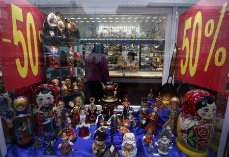 © Reuters. Russian traditional Matryoshka wooden dolls and other gifts are on display, with sale advertisements seen behind a shop window, in St. Petersburg