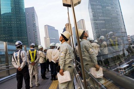 © Reuters. People wearing hard hats inspect a building site from a walkway at the Shiodome business district in Tokyo