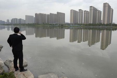 © Reuters. A man talks on his phone near a new residential compound in Taiyuan