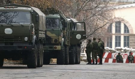 © Reuters. Armed people and military trucks are seen near a checkpoint outside a building on the territory controlled by the self-proclaimed Donetsk People's Republic in Donetsk