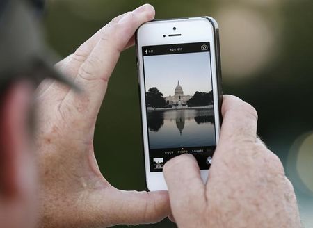 © Reuters. A man takes a photo of the U.S. Capitol, on the eve of a potential federal government shutdown, in Washington