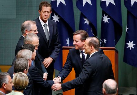 © Reuters. Australia's PM Abbott gestures as he introduces British PM Cameron to members of his cabinet in Australia's House of Representatives chamber in Canberra