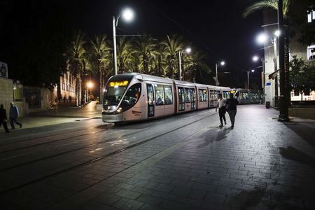 © Reuters. Pedestrians walk as a light rail tram passes by in Jerusalem