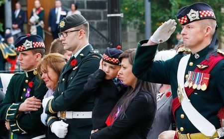 © Reuters. Marcus Cirillo, 5, covers his ears during a salute during the funeral procession for his father, Cpl. Nathan Cirillo in Hamilton, Ontario October 28, 2014 as Cirillo's mother, Kathy Cirillo and his sister Natasha Cirillo look on