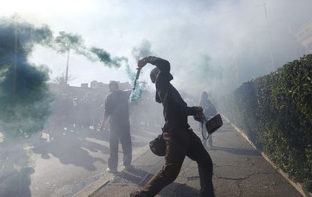 © Reuters. Un manifestante lancia un fumogeno durante la manifestazione di oggi a Roma