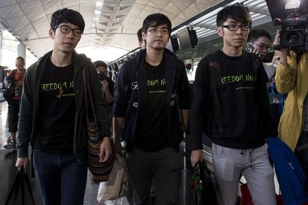 © Reuters. Hong Kong Federation of Students leader Alex Chow, committee members Nathan Law and Eason Chung react after being refused to board the plane at the Hong Kong International Airport