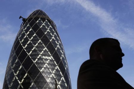 © Reuters. A City worker is silhouetted in front of the 'Gherkin' building in the City of London