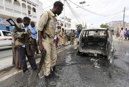 © Reuters. A soldier examines a car that exploded, leaving one person dead, along Maka Al Mukarama street in Mogadishu