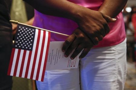 © Reuters. A woman holds U.S. flag during the oath of allegiance to the United States during a naturalization ceremony in New York