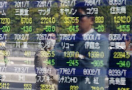 © Reuters. Passers-by are reflected on an electronic stock quotation board outside a brokerage in Tokyo