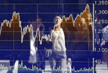 © Reuters. Reflexo de pedestres em uma vitrine de um corretora que mostra um gráfico com as flutuações da Bolsa de Tóquio, em Tóquio