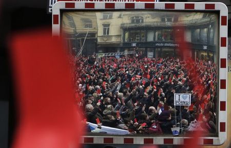 © Reuters. Demonstrators are reflected in a mirror showing symbolic red cards to Czech President Milos Zeman during a protest rally in Prague