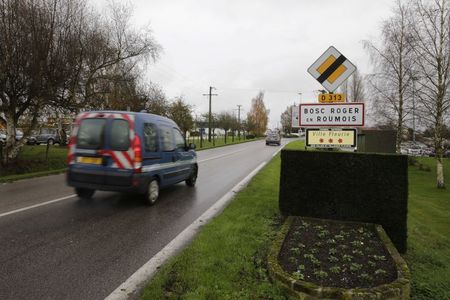 © Reuters. A French National Gendarmerie car drives past the road sign at the entry of Le Bosc-Roger-en-Roumois, northern France