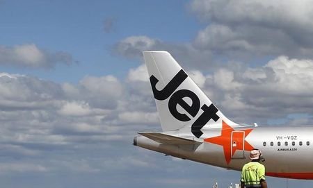 © Reuters. File photo of an airport worker in front of a Jetstar passenger plane in Melbourne