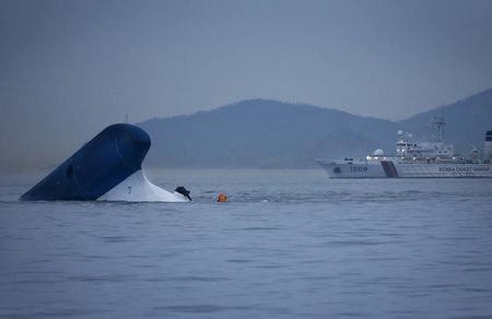 © Reuters. Coast Guard ship passes near the upturned South Korean ferry "Sewol" in the sea off Jindo